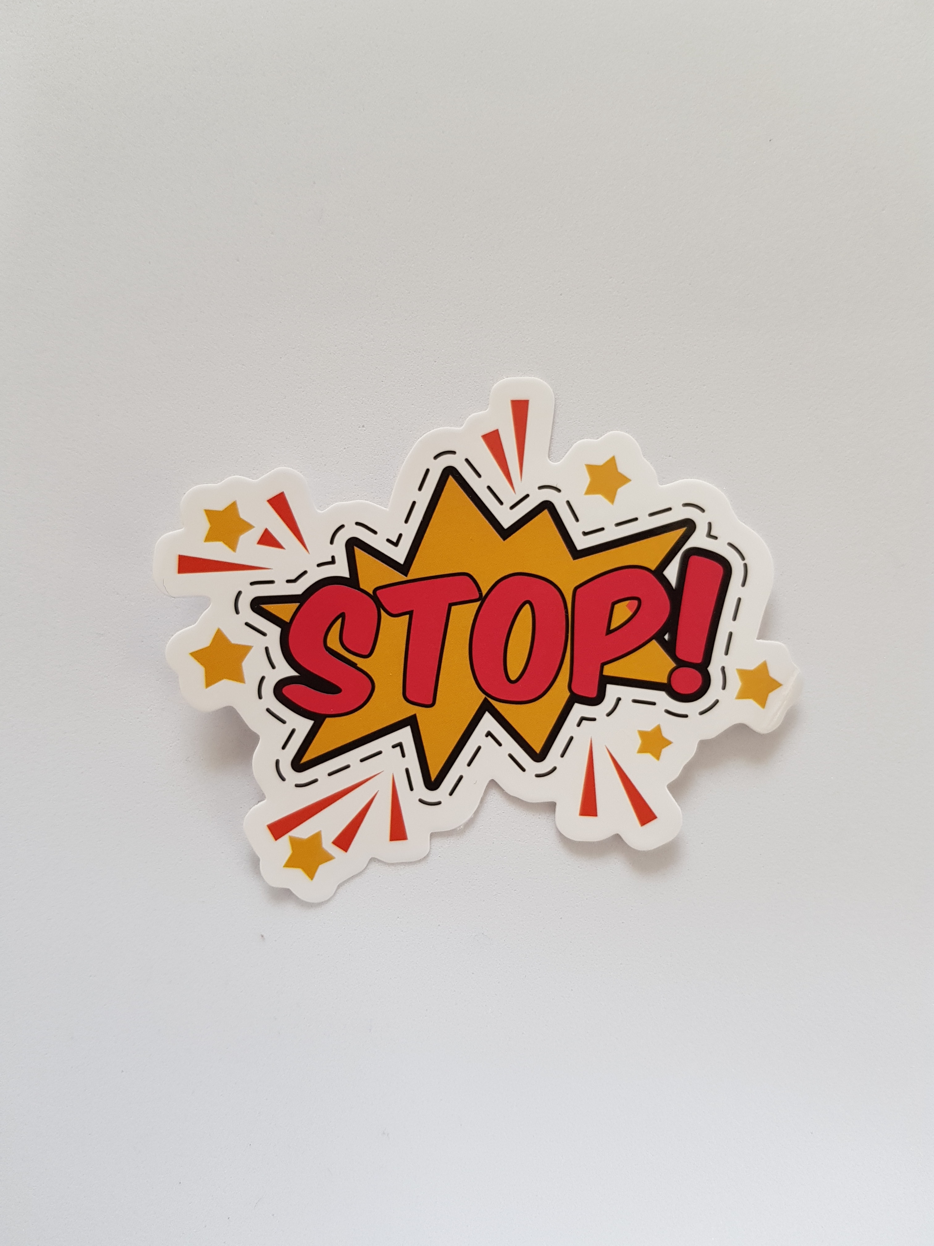 Foto von einem knalligen orange-gelb-farbenen Papierschild auf dem in roter Schrift "Stop!" steht. 